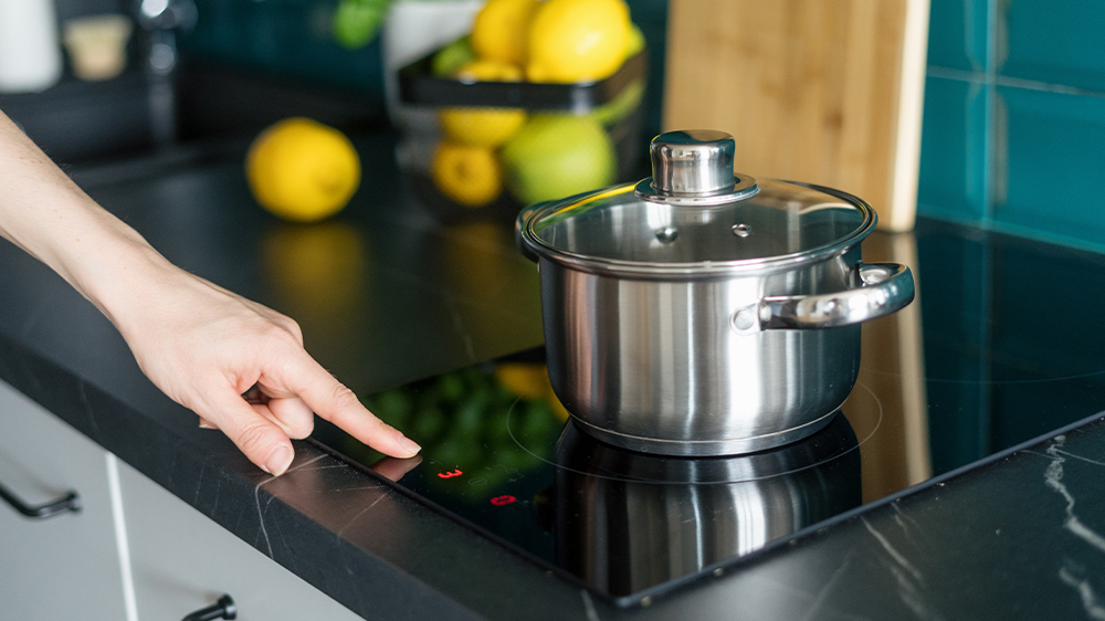 Žena vaří vodu v hrnci na indukční varné desce_02