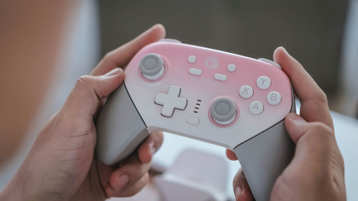 Ruky držia herný ovládač GameSir Super Nova Whipped Pink