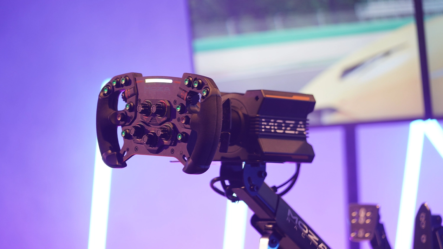 Monitor na pozad&iacute; a z&aacute;kladna MOZA na drž&aacute;ku s volantem