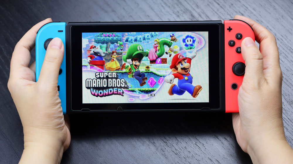 Ruce držící herní zařízení Nintendo Switch s hrou Super Mario_02