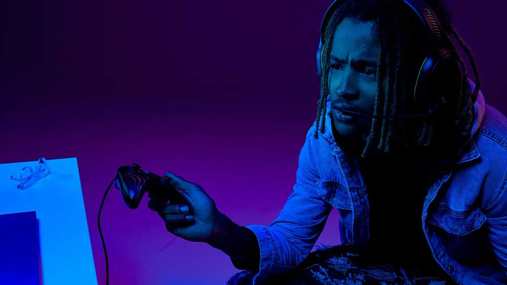 Mladý muž hraje hru s gamepadem PDP Afterglow Wave Wired Controller pro Xbox/PC a má nasazený herní headset_03