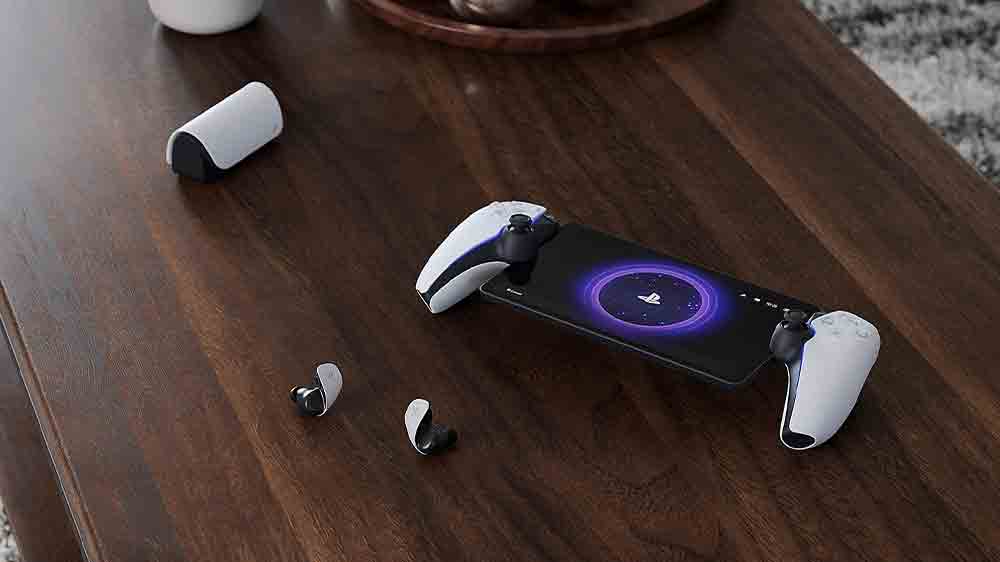 D&aacute;lkov&yacute; přehr&aacute;vač Sony PlayStation Portal PS5 položen&yacute; na stole společně se sluch&aacute;tky_2