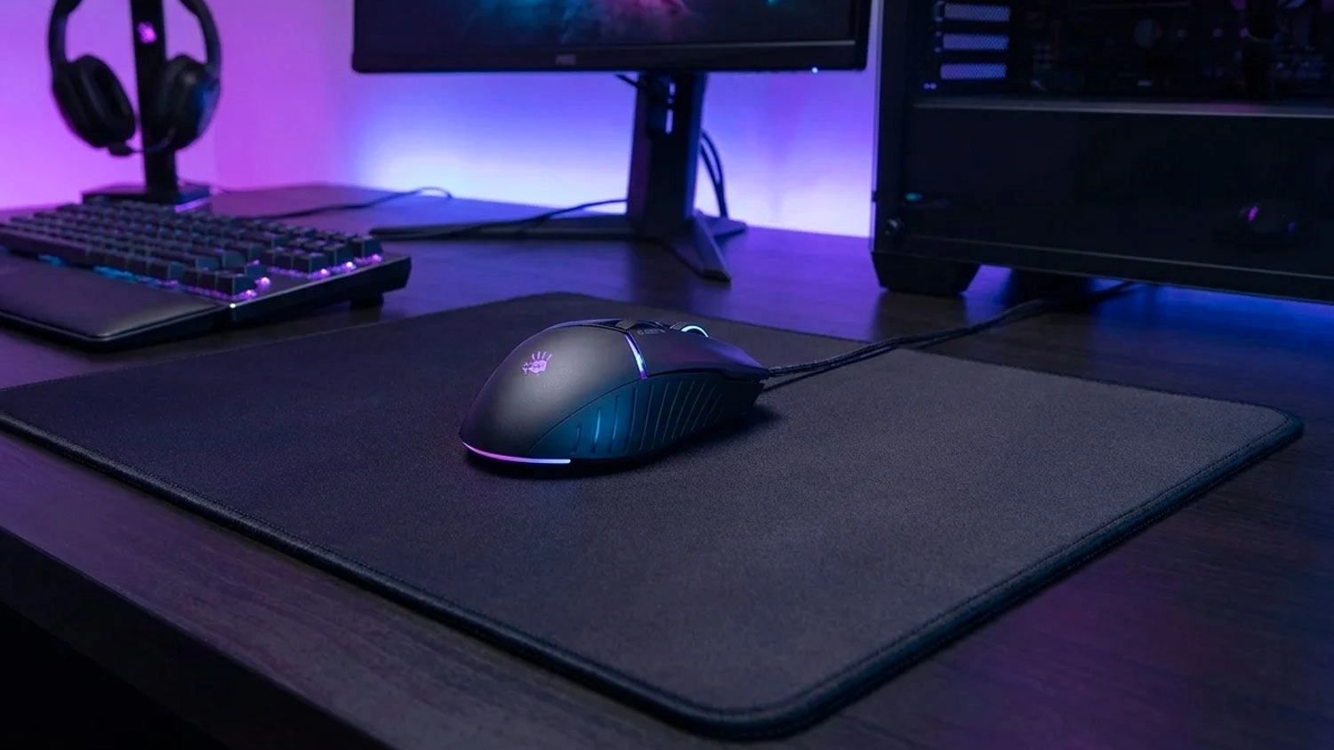 Herní myš A4Tech Bloody W95 MAX Black s RGB podsvícením na černé podložce na herním stole.
