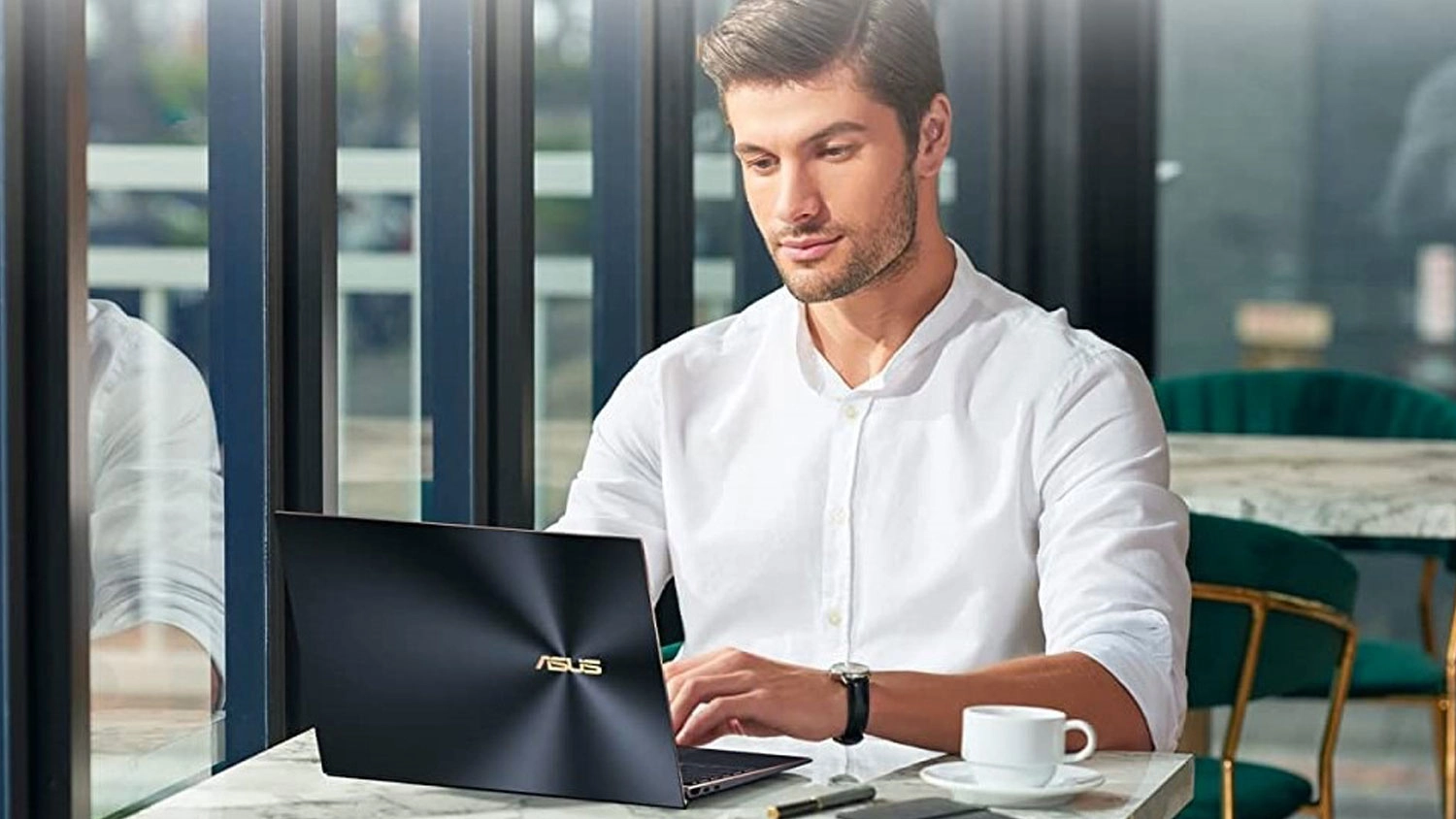 Muž v kavárně sedí u notebooku Asus