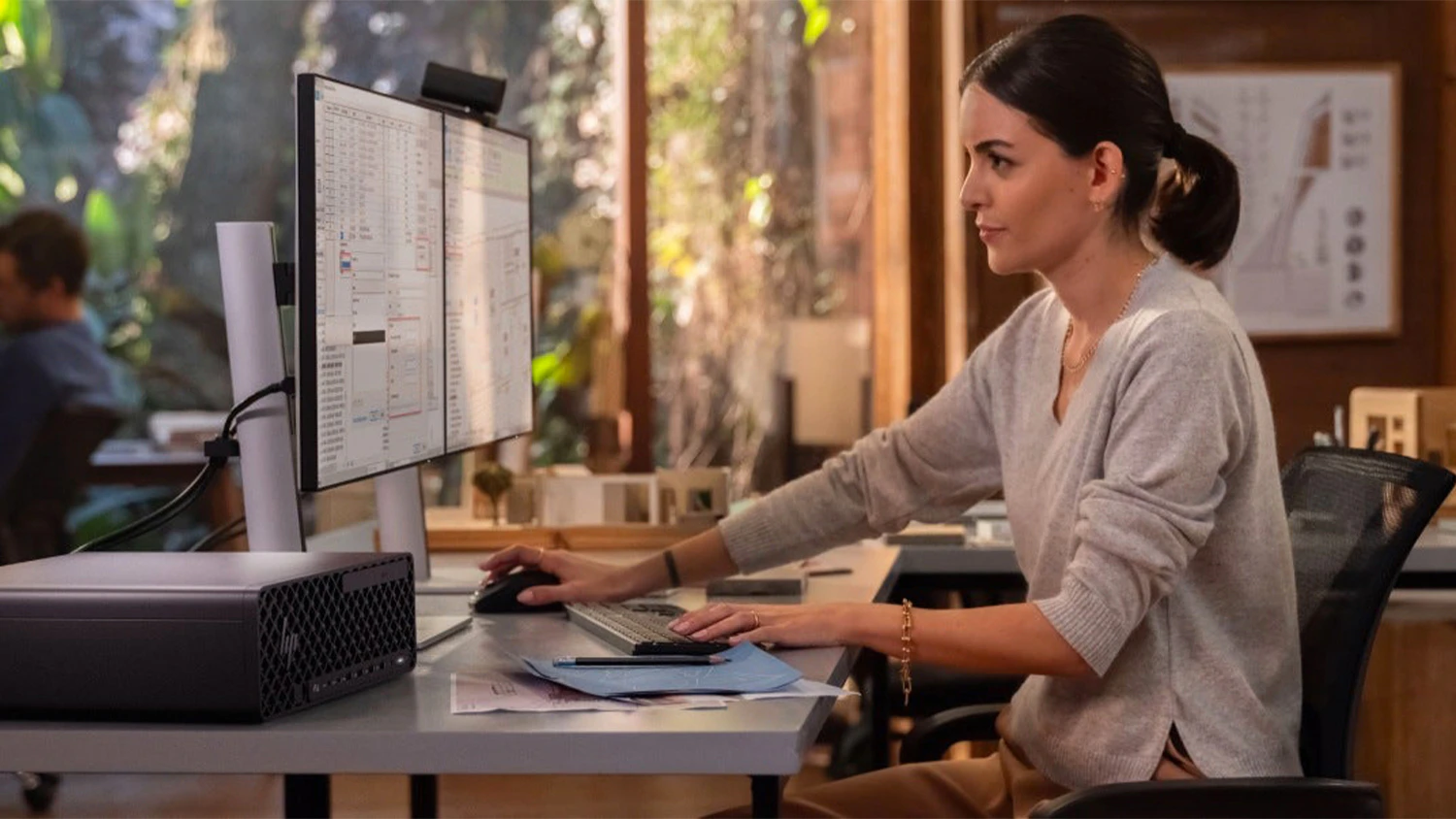 Žena v kanceláři u stolu s monitorem a počítačem HP