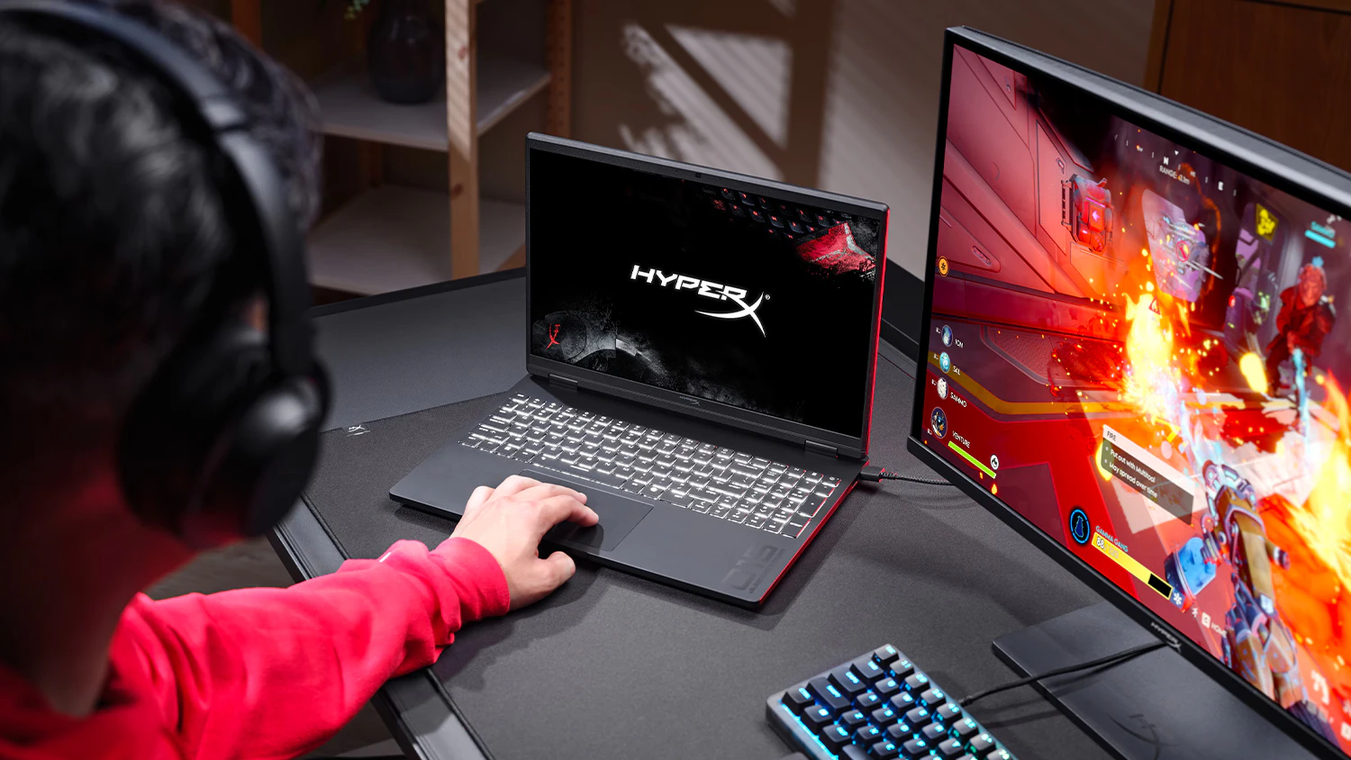 Osoba hrající hru u stolu s notebookem HyperX