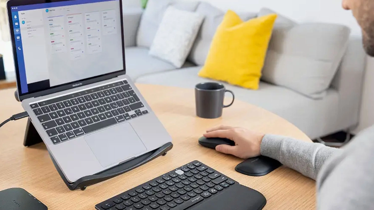 Muž pracuj&iacute;c&iacute; u notebooku s rukou položenou na ergonomick&eacute; opěrce z&aacute;pěst&iacute; Kensington ErgoSoft u poč&iacute;tačov&eacute; my&scaron;i.