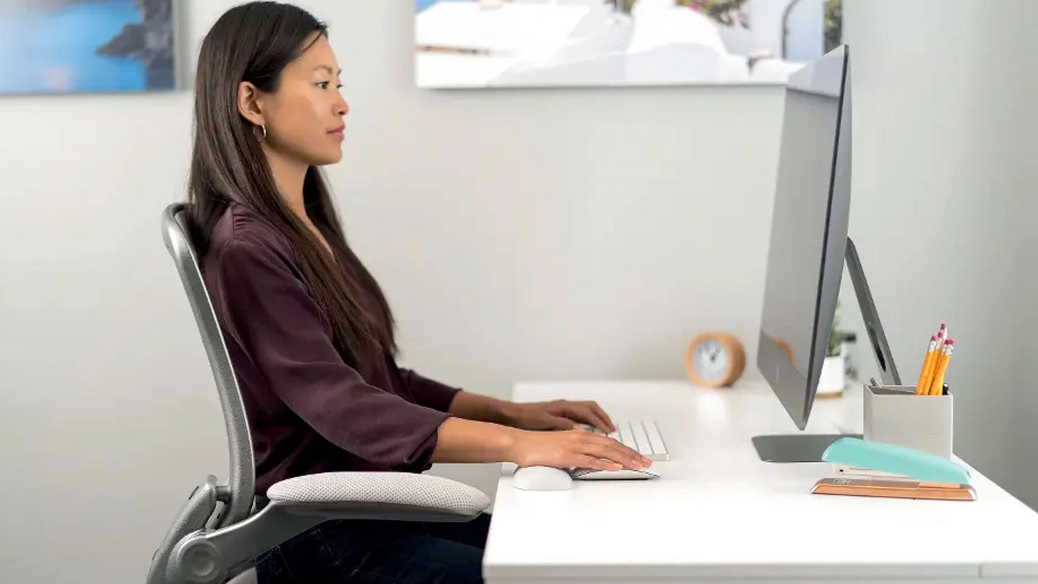 Žena pracující u notebooku s rukou položenou na ergonomické opěrce zápěstí Kensington ErgoSoft u počítačové myši.