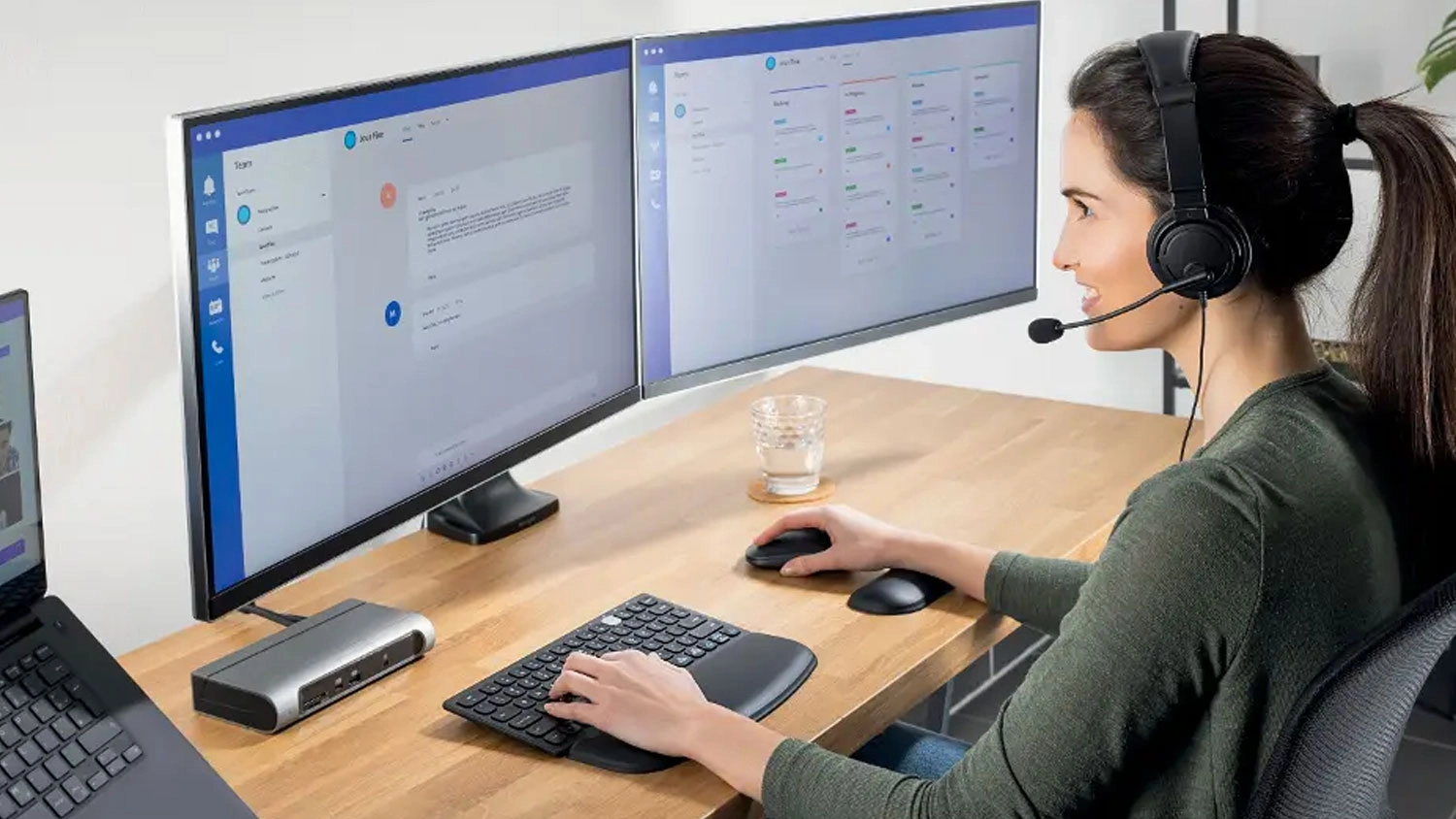 Žena pracující u počítače s headsetem používá kompaktní klávesnici s ergonomickou opěrkou Kensington ErgoSoft.