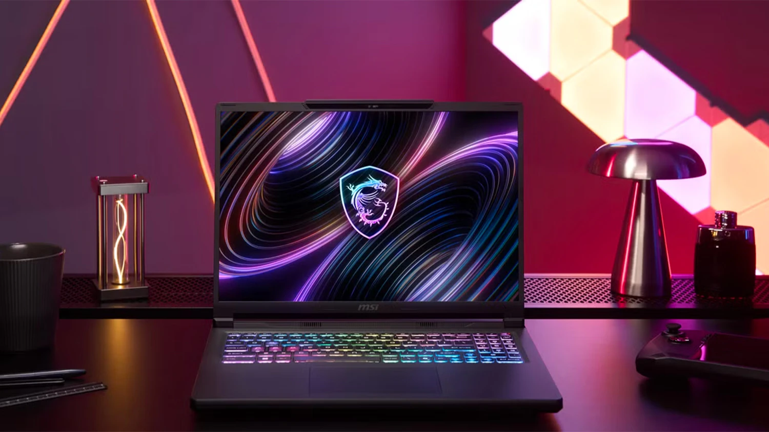 Stůl s dekoracemi a růžovým pozadím a notebook MSI