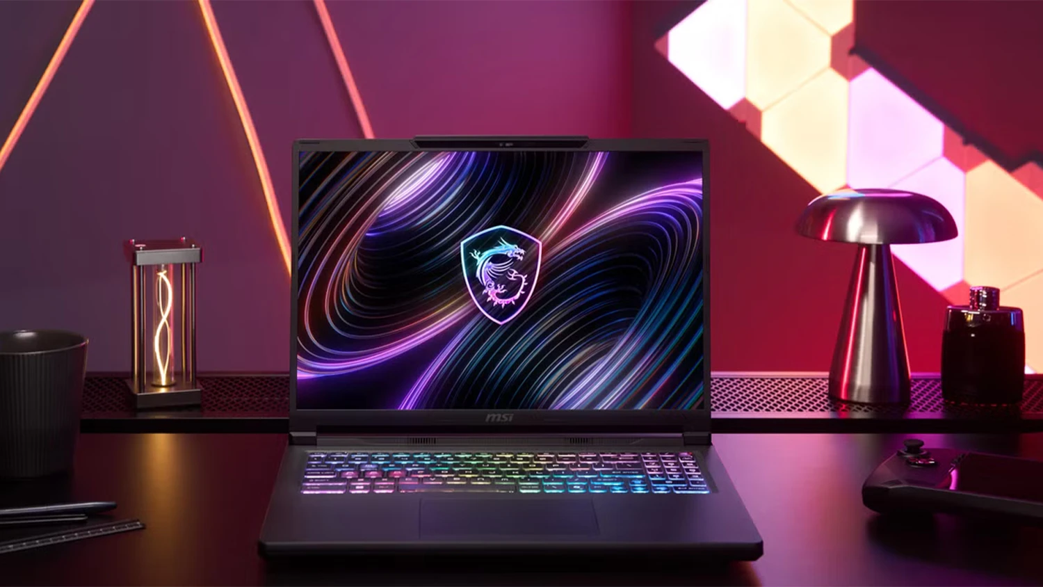 Stůl s dekoracemi a růžovým pozadím a notebook MSI