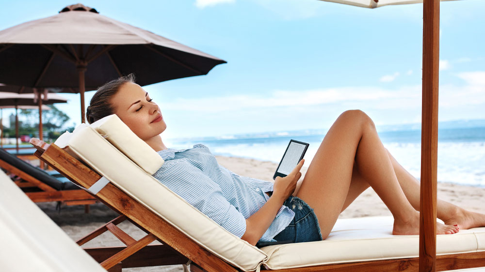 Žena si číta z čítačky kníh počas dovolenky pri mori_04