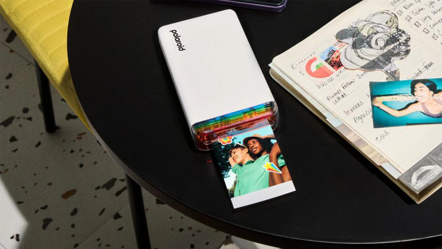 Stolek s deníkem, fotografiemi a tiskárnou Polaroid