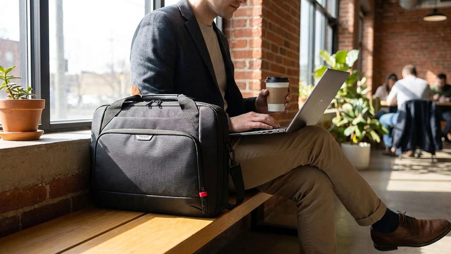 Muž na nádraží sedi na lavičce s brašnou pro notebook Targus Classic