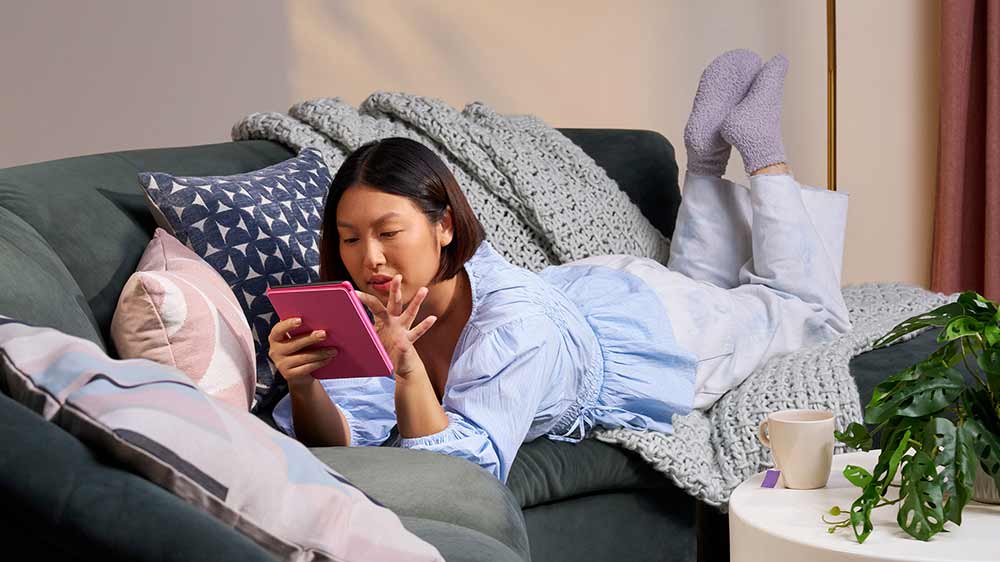 Žena leží na gauči a čte si se čtečkou Kindle_03