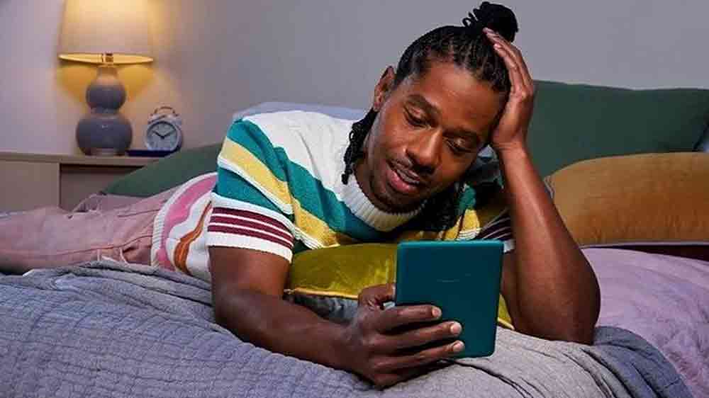 Muž leží na posteli a číta na čítačke kníh Amazon Kindle Paperwhite 2024_04