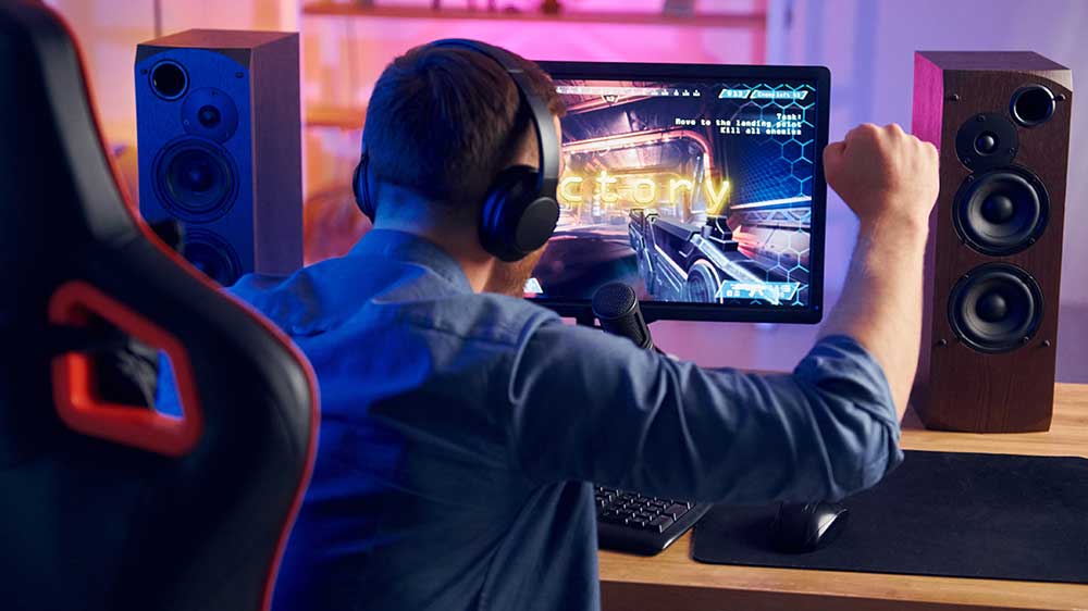 Mladý hráč se raduje z vítězství v akční hře, kterou hraje na monitoru_02