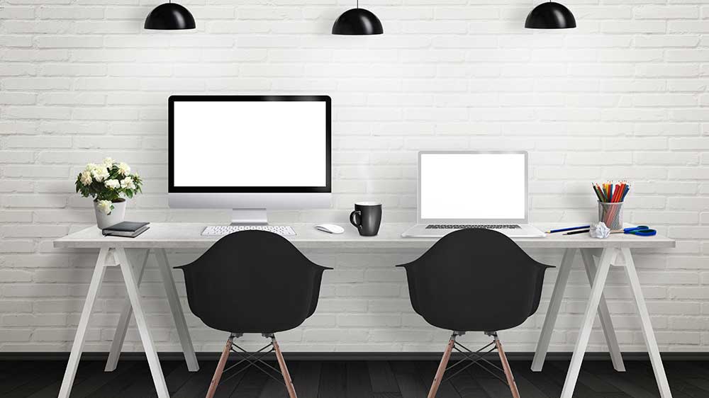 Dlouhý bílý pracovní stůl se dvěma židlemi a na desce PC monitor a otevřený notebook s příslušenstvím_02