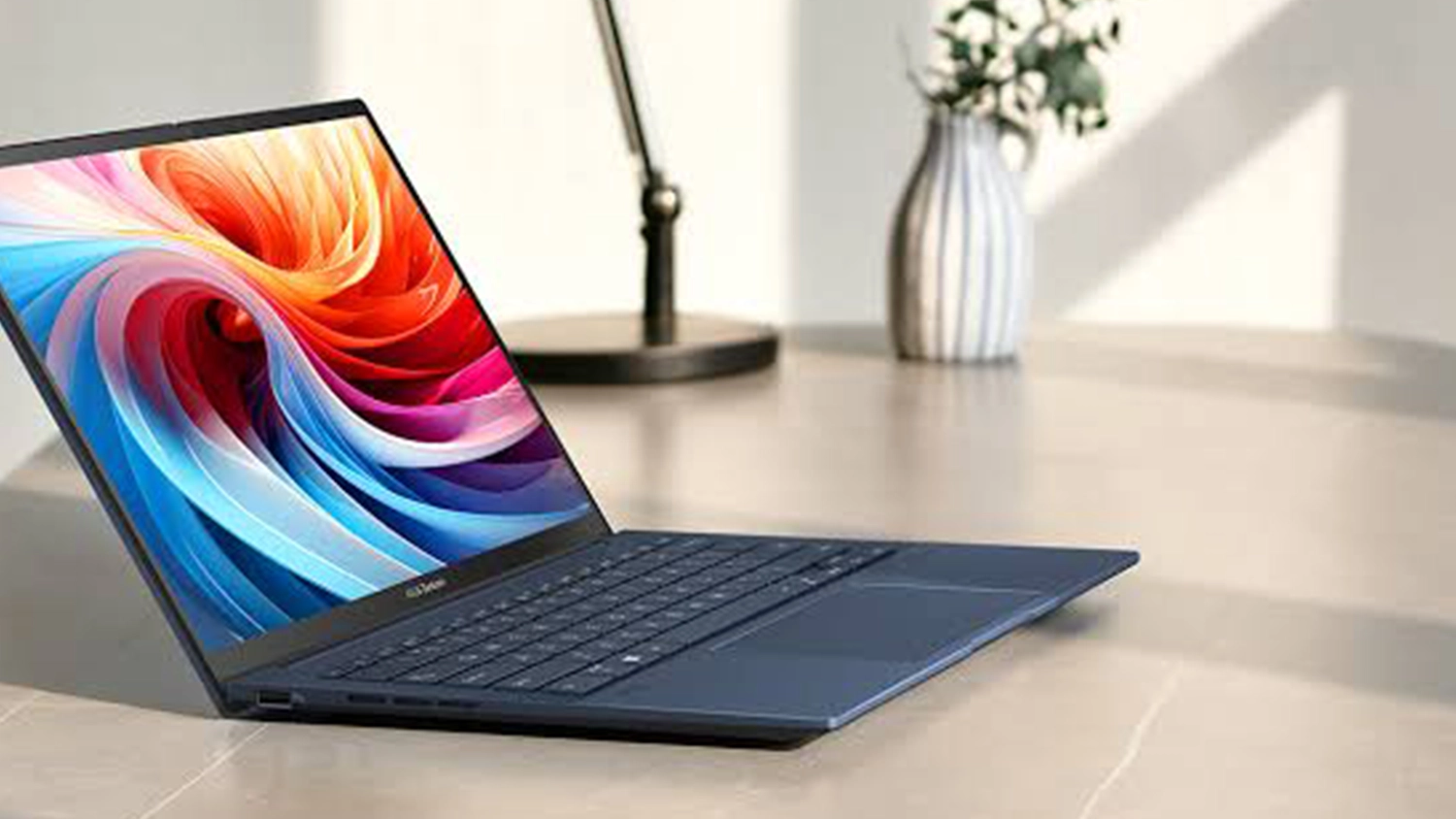 Stůl s lampičkou a květinou za notebookem ASUS