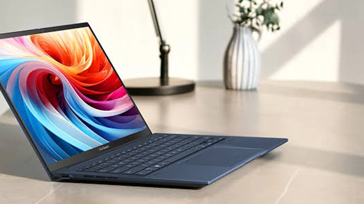 Stůl s lampičkou a květinou za notebookem ASUS
