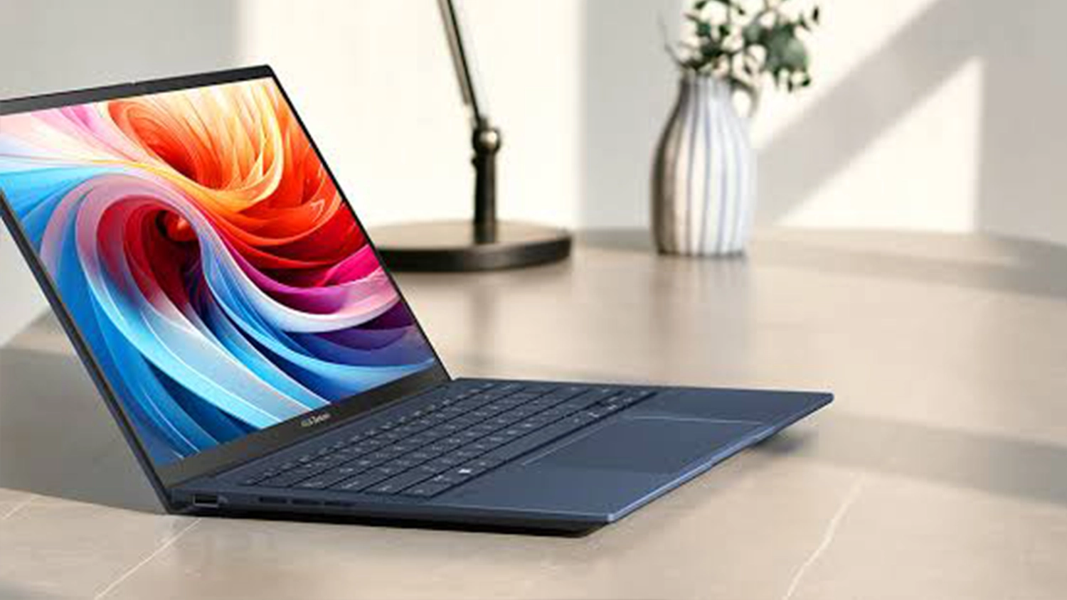 Stůl s lampičkou a květinou za notebookem ASUS