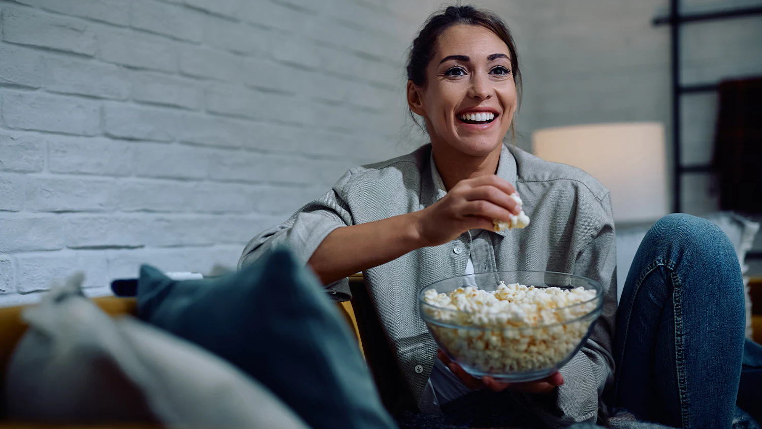 Žena sleduj&uacute;ca film s popcornom v ruke