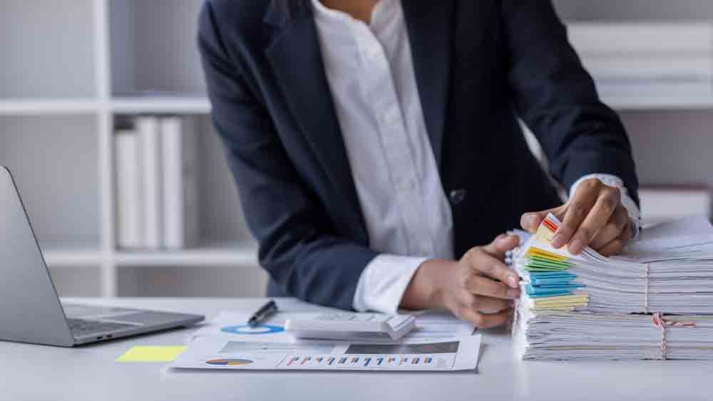 Člověk prohrabující se stohem potištěných papírů_04