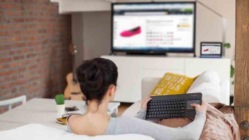 Žena sediaca na sedačke ovl&aacute;da telev&iacute;zor pomocou kl&aacute;vesnice s touchpadom_02
