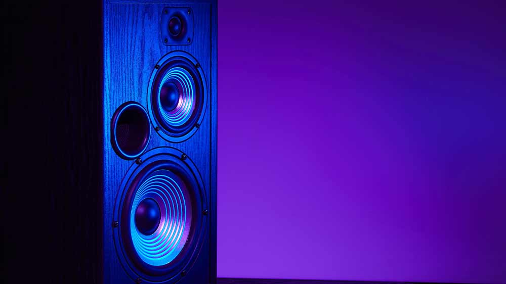 Reproduktor stojící na zemi v místnosti s neonovým fialovým světlem_02