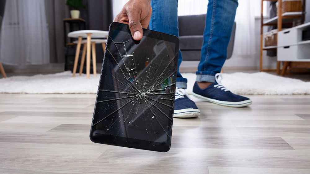 Muž chytající tablet při pádu na podlahu s prasklým displejem_02