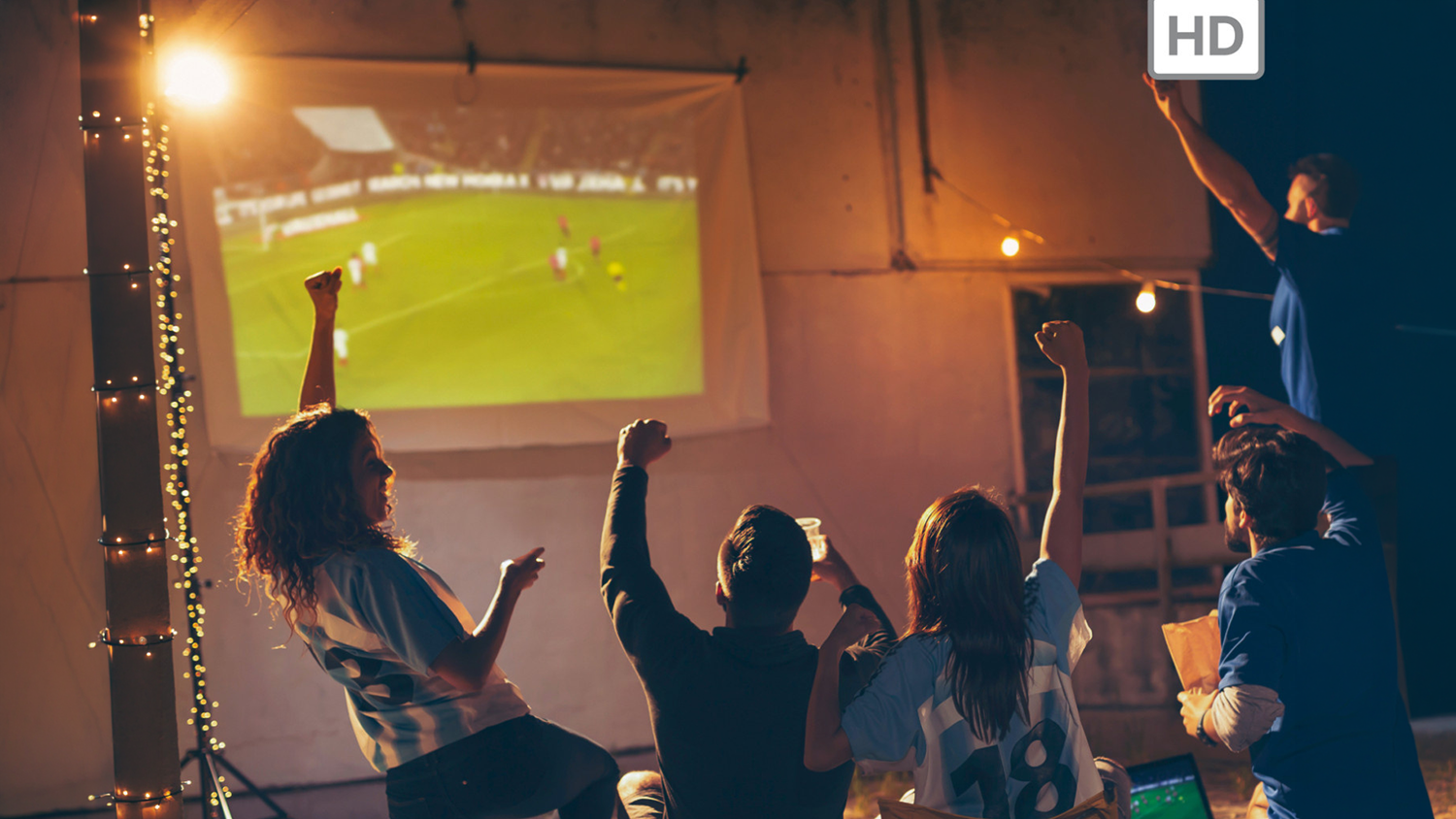 Skupina mlad&yacute;ch ľud&iacute; sleduje futbal na pl&aacute;tne