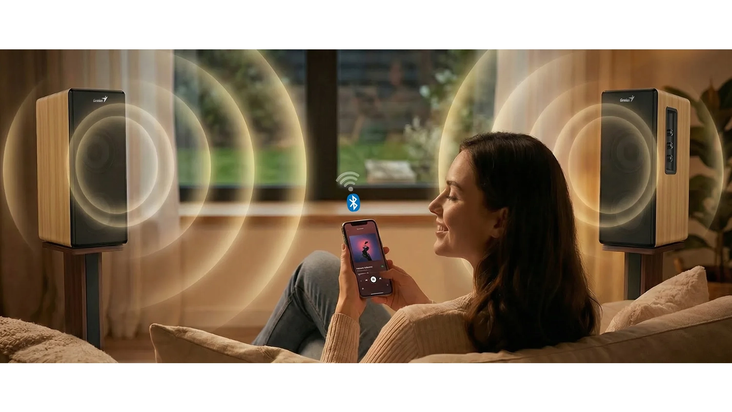 Žena sedí na gauči a pouští si hudbu přes Bluetooth v reproduktorech Genius SP-HF1220BT