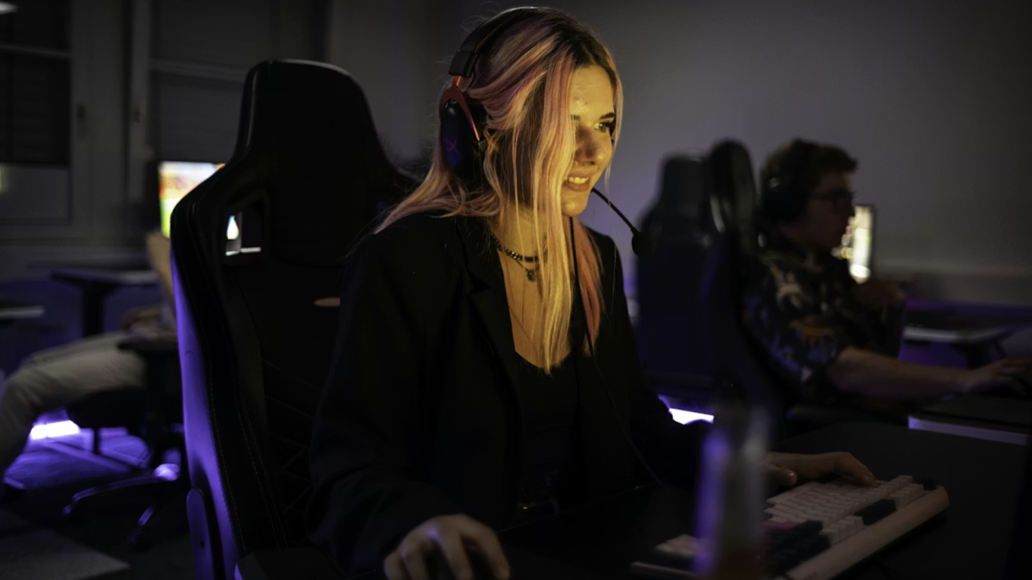 Žena se sluchátky hrající počítačovou hru u stolu
