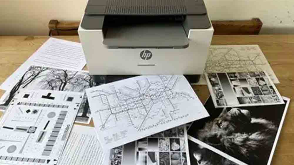 Laserová tiskárna HP LaserJet M209DW na pracovním stole s vytištěnými dokumenty_02