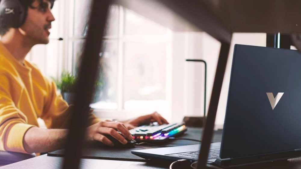 Muž u stolu s HP Victus Gaming 16-r1002nc_03