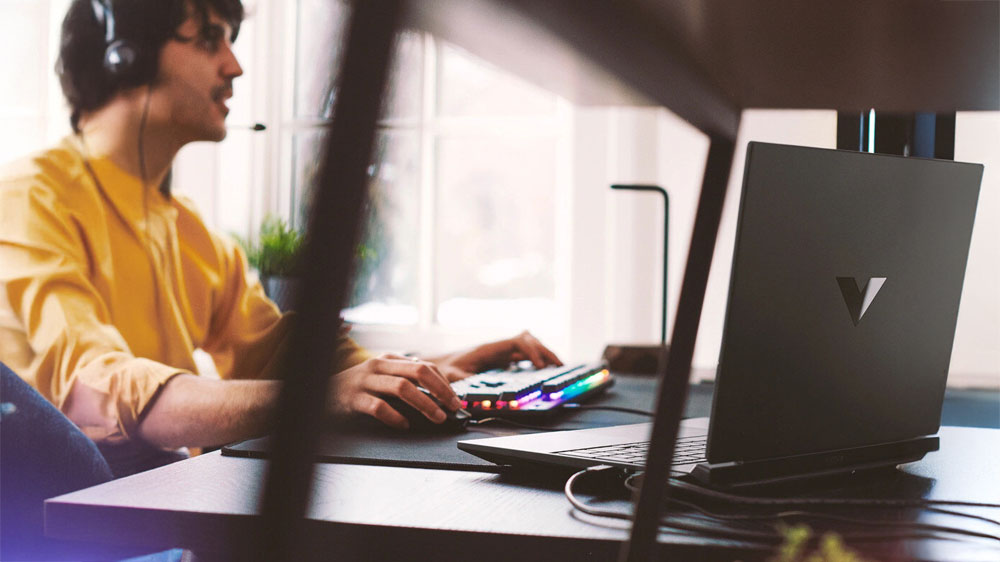 Muž u pracovního stolu s klávesnicí a notebookem HP Victus Gaming 15-fa1035nc_4