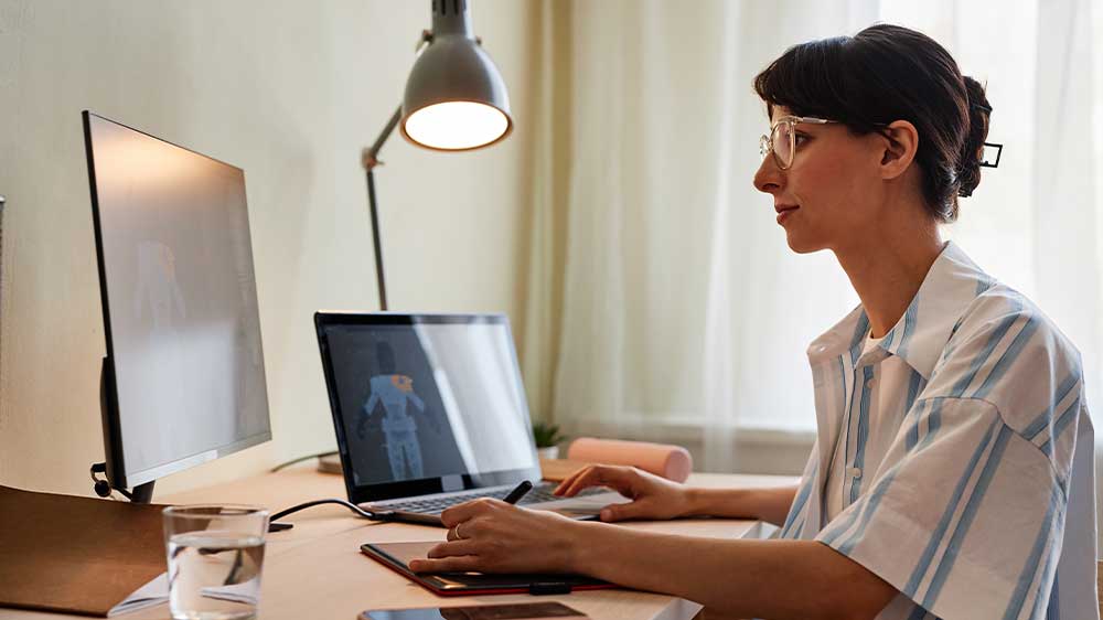 Žena vytváří 3D modely na tabletu a na notebooku s připojeným monitorem_03