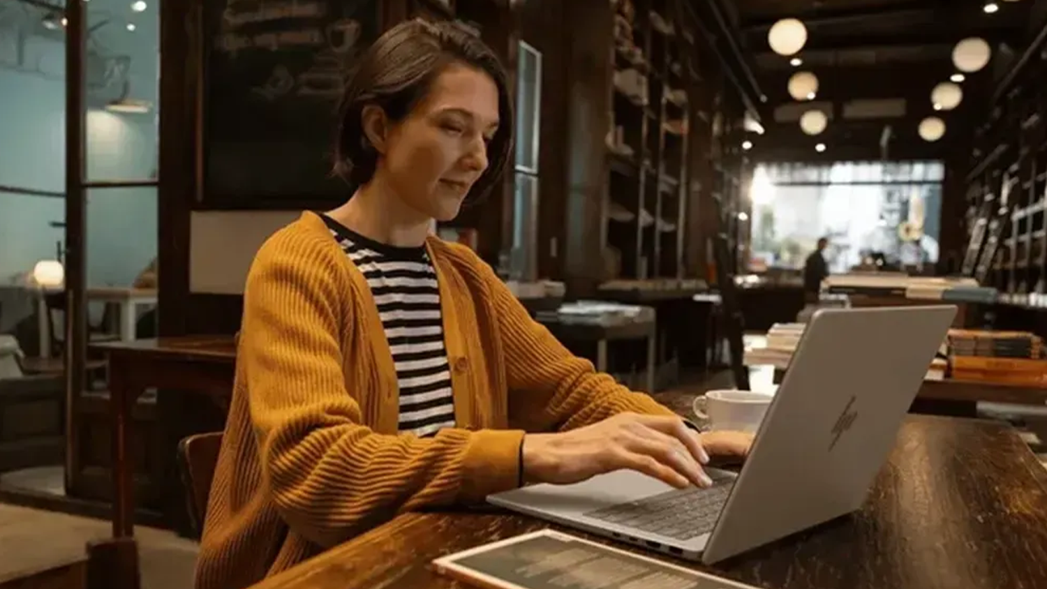 Žena v kaviarni pri notebooku HP OmniBook 7