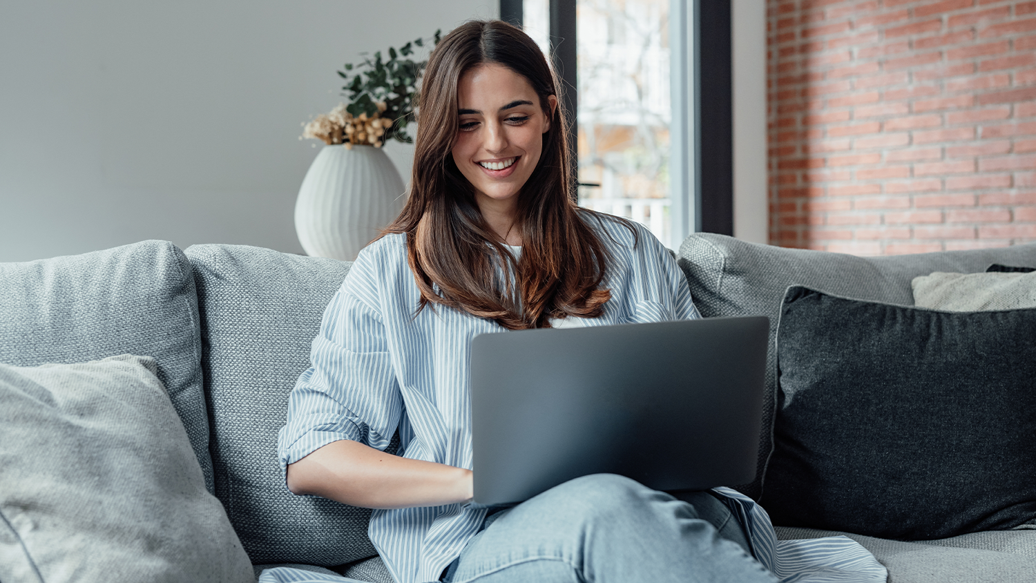 Žena sed&iacute; na pohovce a pracuje na notebooku