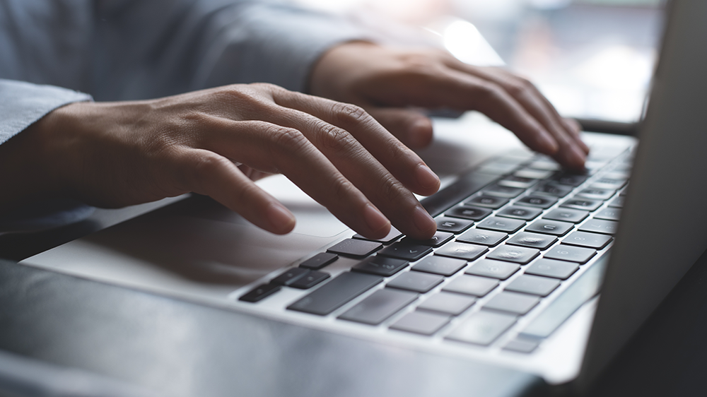 Žensk&eacute; ruce p&iacute;&scaron;ou na kl&aacute;vesnici notebooku