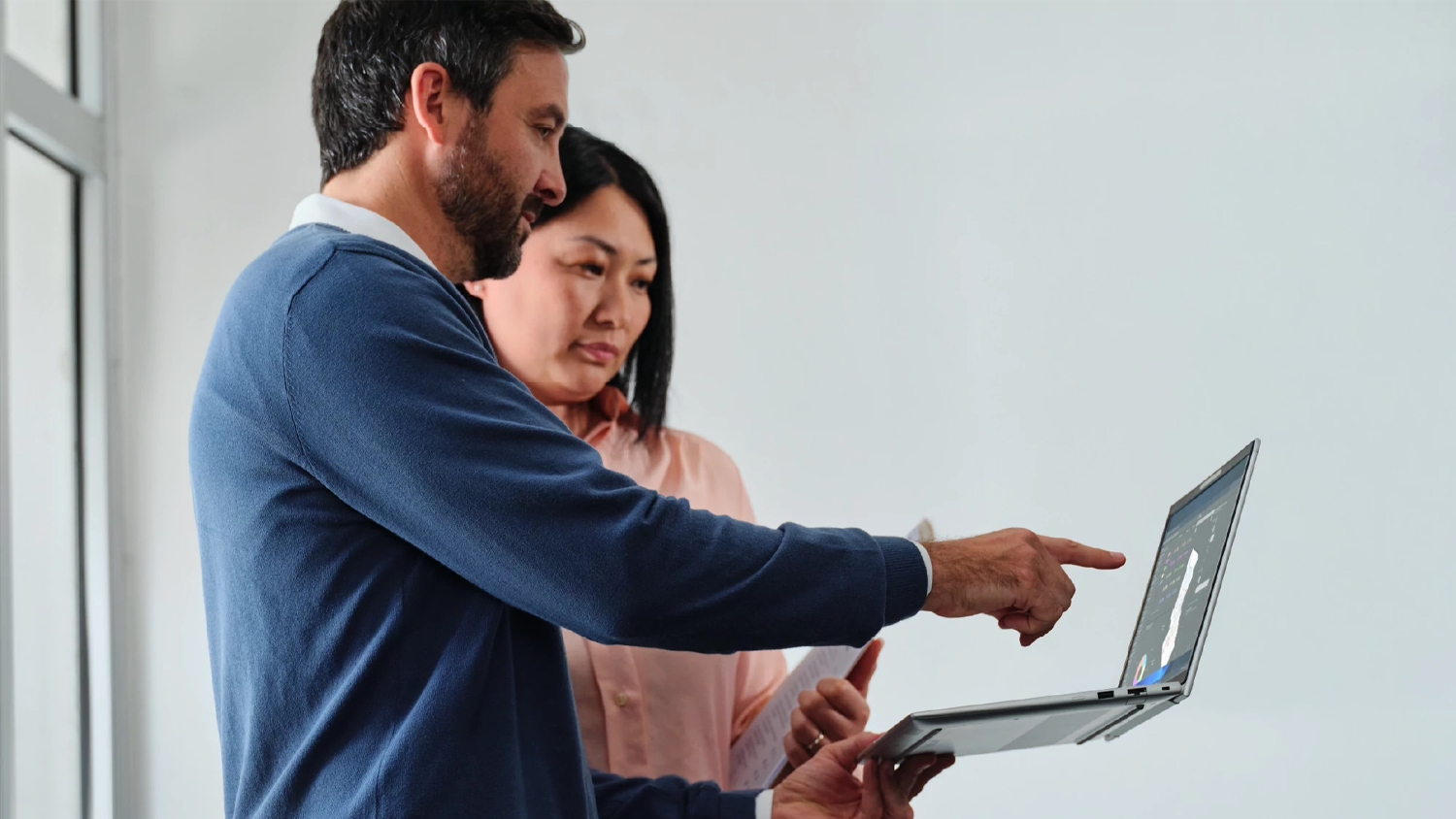 Muž ukazuj&iacute;c&iacute; ženě informace na notebooku HP EliteBook 8 G2a