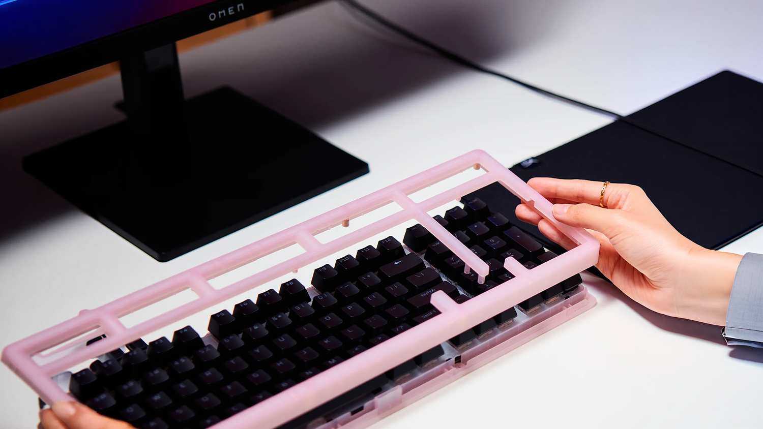 Hráč si mění kryt klávesnice HyperX Origins 2 1800 Housing před monitorem