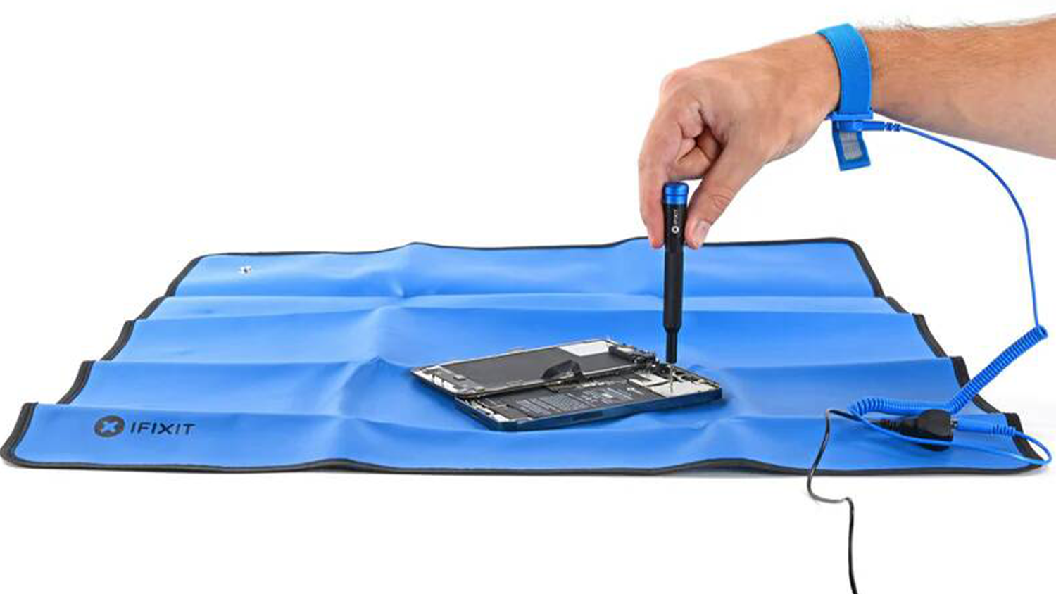 Ruka opravuje na antistatické podložce iFixit Portable zařízení