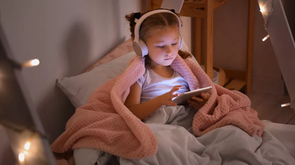Holčička na tabletu se sluchátky zabalená v dece_03
