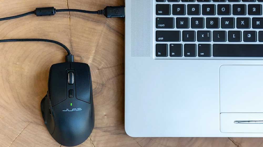 Bezdrátová myš JLAB JBuds položená vedle počítače_03