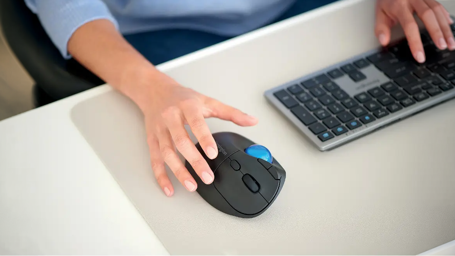 Ruce na stole s klávesnicí a myší Kensington EQ Pro Fit Ergo TB450 Trackball