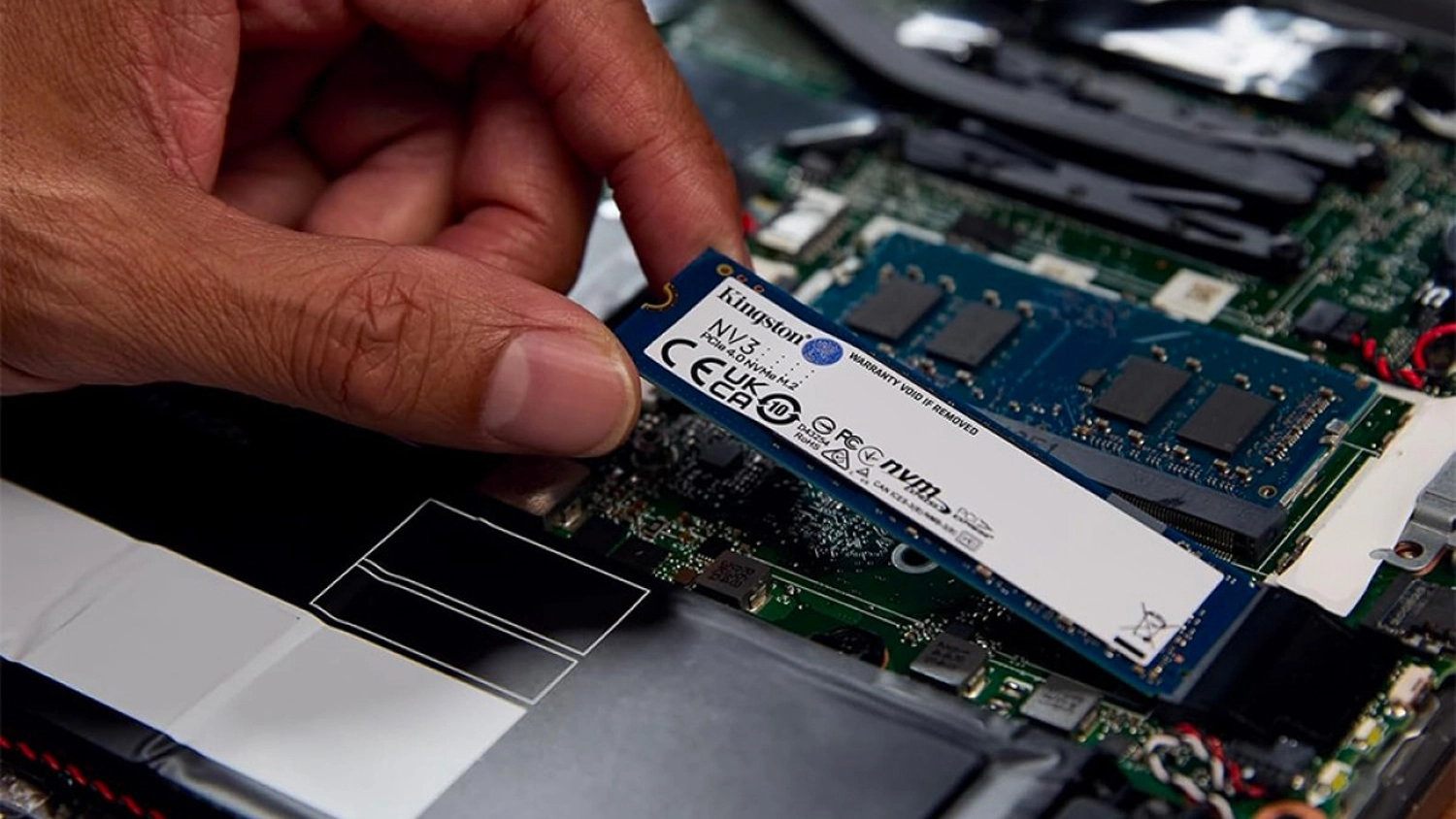 Ruka vkládající SSD disk Kingston NV3 do notebooku