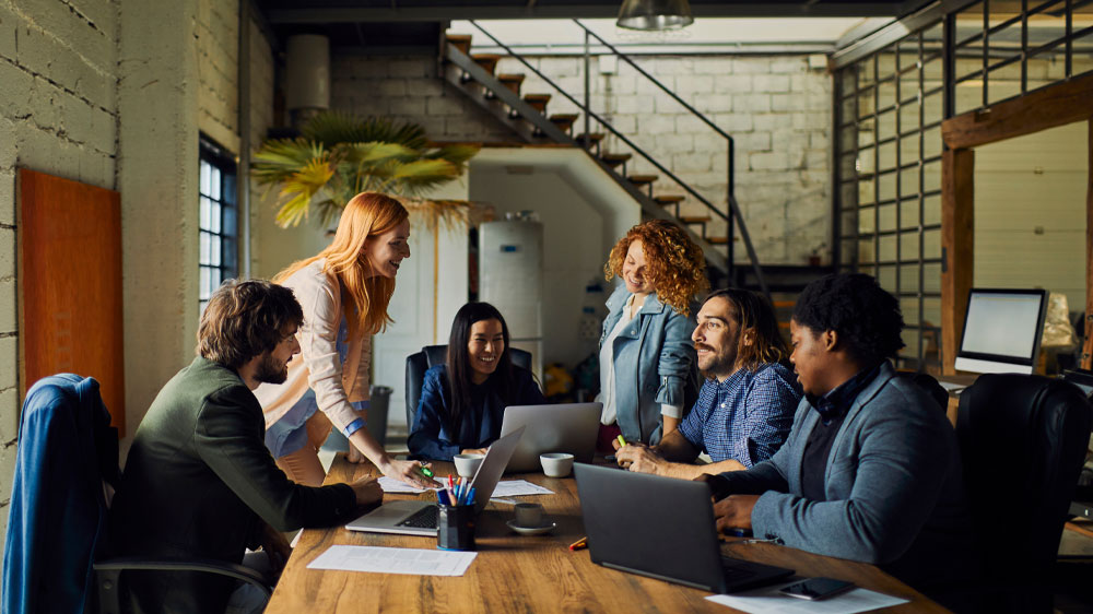 Mladí kolegové diskutují při teambuildingu v kanceláři a mají otevřené notebooky Lenovo ThinkPad T14s G4 Ryzen 5 Pro 7540U_02