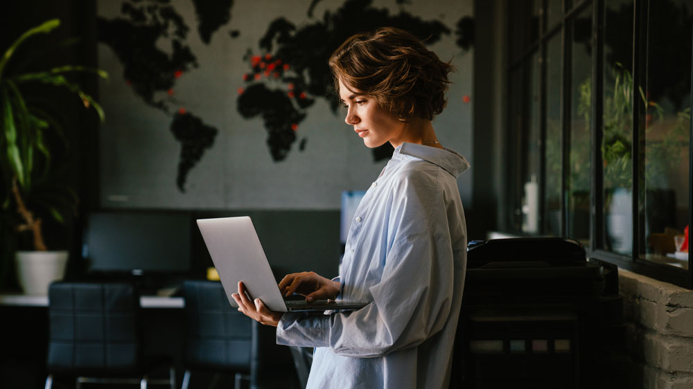 Mladá žena ve stoje v kanceláři drží v ruce notebook Lenovo ThinkPad T14s G4 Ryzen 5 Pro 7540U_03