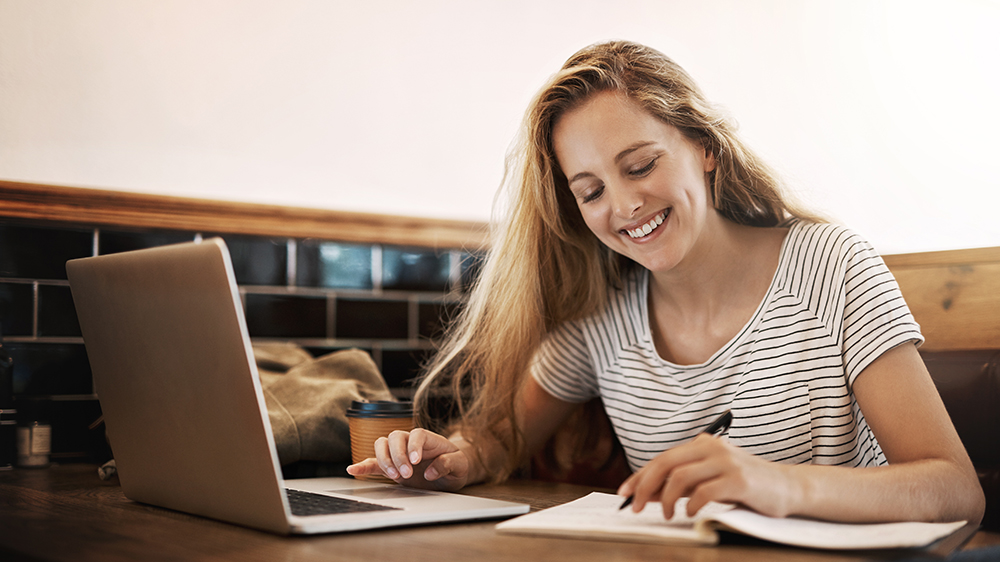 Mladá žena se věnuje studiu na notebooku a zapisuje si poznámky_02